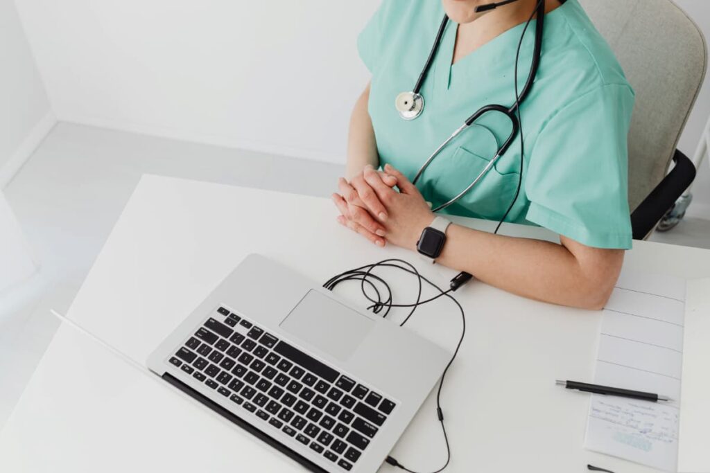 Profissional da saúde usando o laptop, representando os benefícios da prescrição digital.