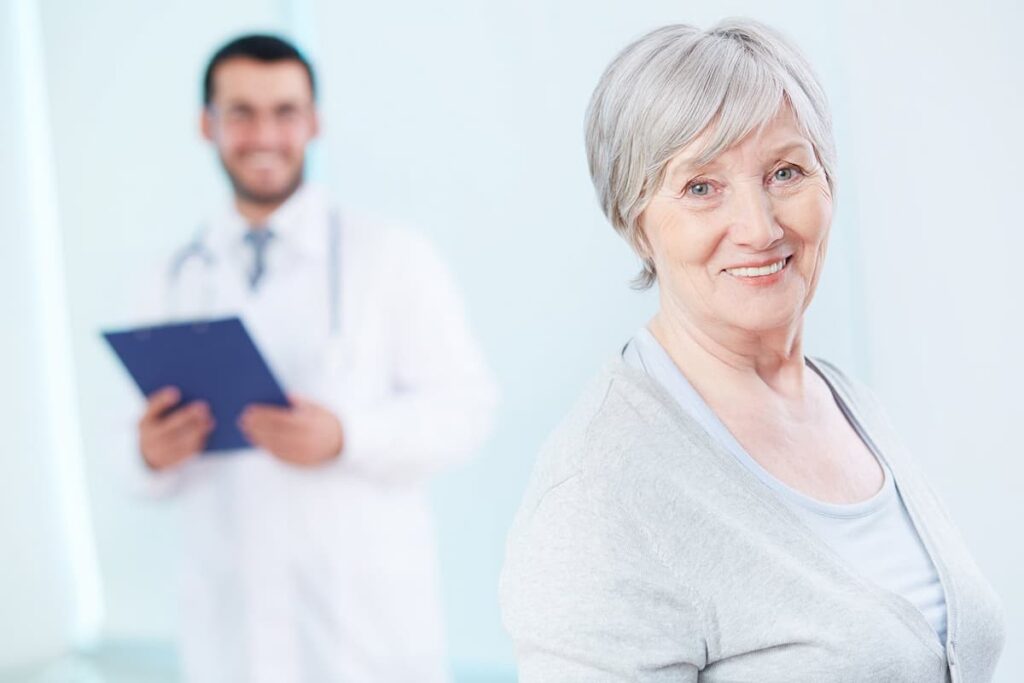 Médico e paciente idosa sorrindo, representando o marketing para clínica de geriatria.