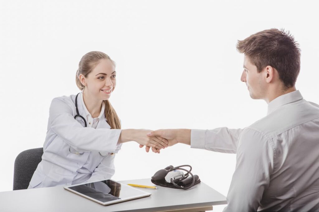 Médica cumprimentando um representante farmacêutico com um aperto de mão.
