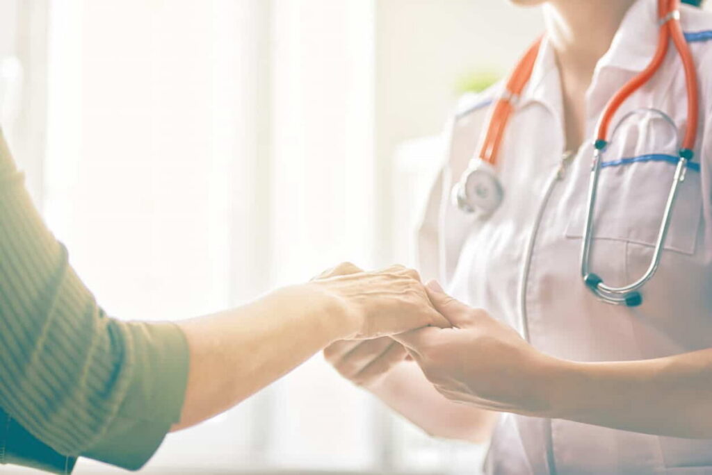 Profissional da saúde segurando a mão do paciente, representando os benefícios da medicina integrativa.