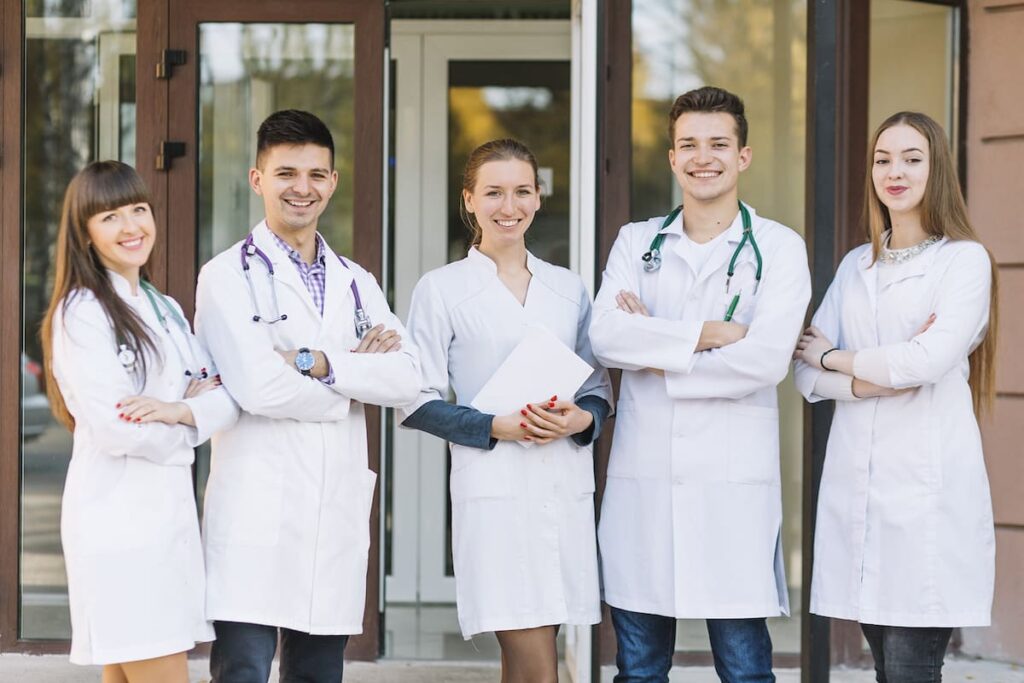 Cinco profissionais da saúde juntos , simulando um coworking para médicos.