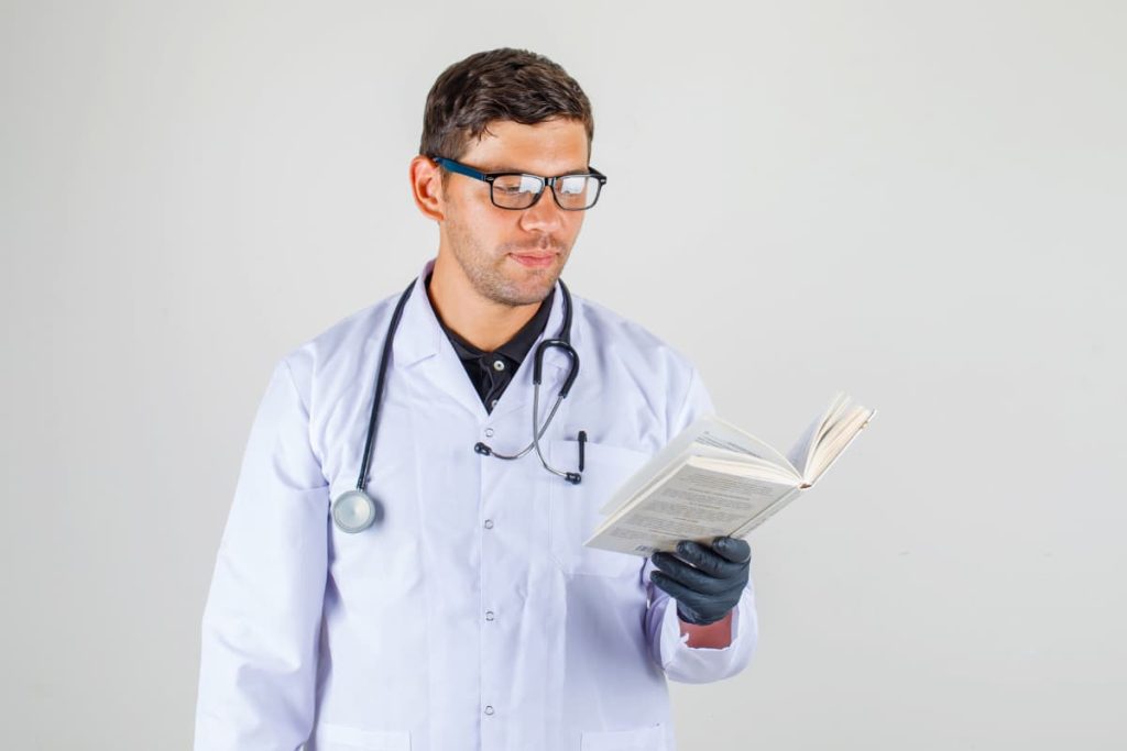 Imagem de um médico lendo um livro, destacando a importância de livros para médicos na formação e atualização profissional.