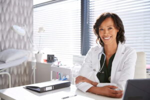 Médico em frente ao laptop para analisar as diferenças entre consultório, clínica e centro médico.