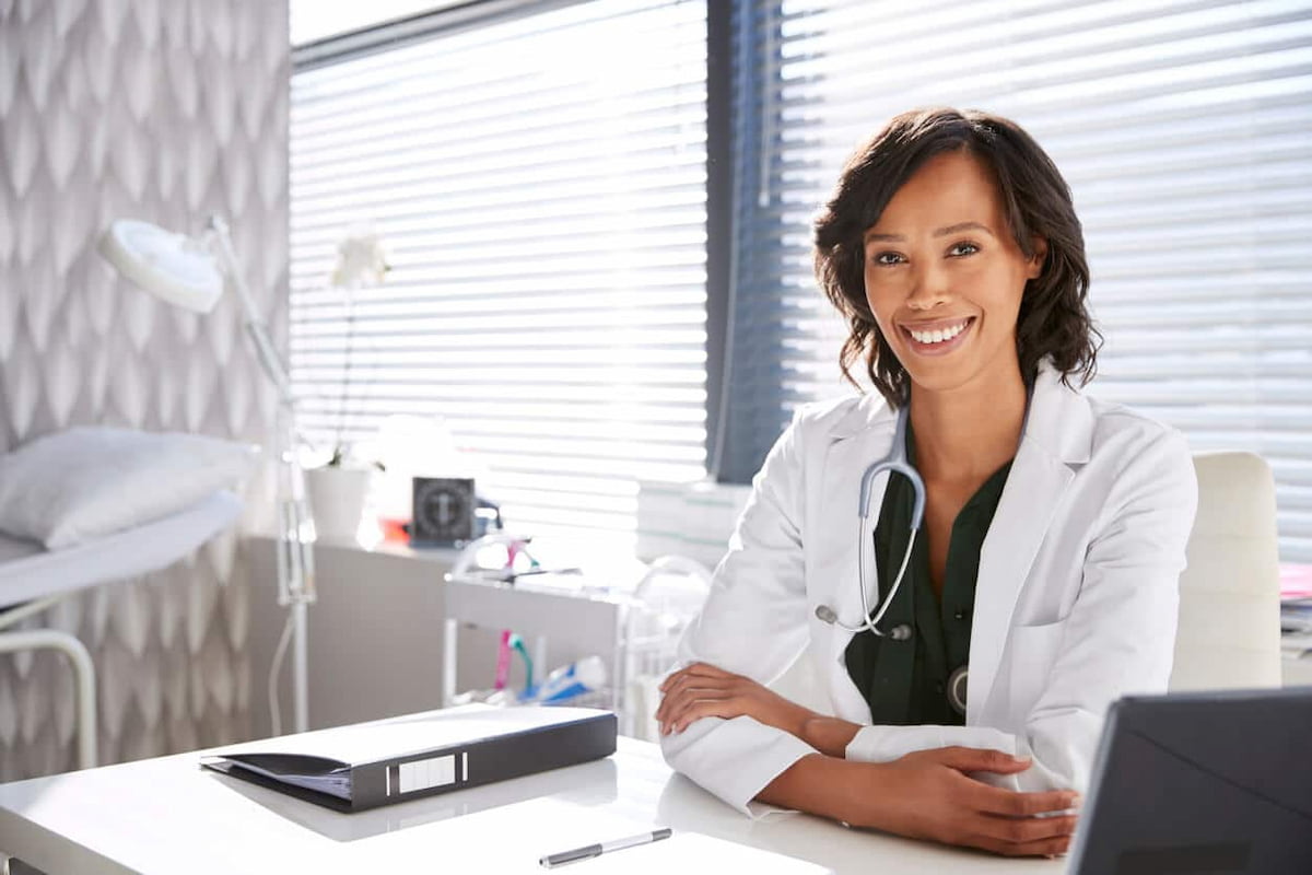 Médico em frente ao laptop para analisar as diferenças entre consultório, clínica e centro médico.