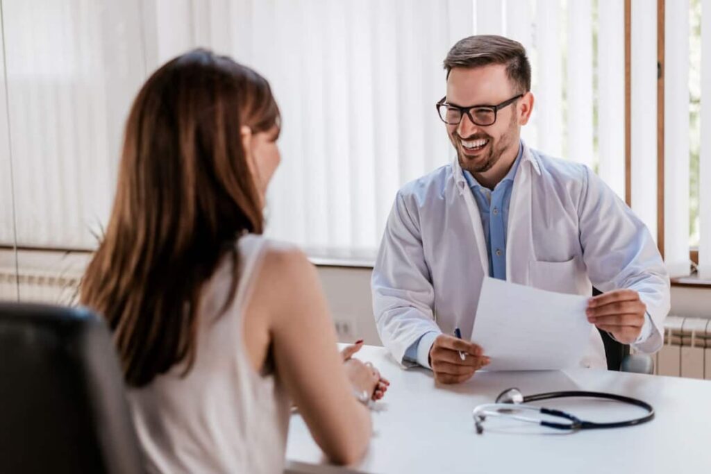 Médico atencioso com prontuário em atendimento humanizado a paciente.