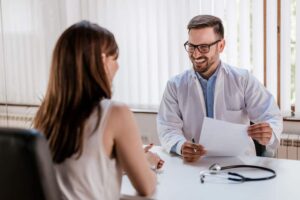 Médico atencioso com prontuário em atendimento humanizado a paciente.
