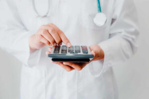 Médico segurando calculadora, simbolizando controle de fluxo de caixa na saúde.