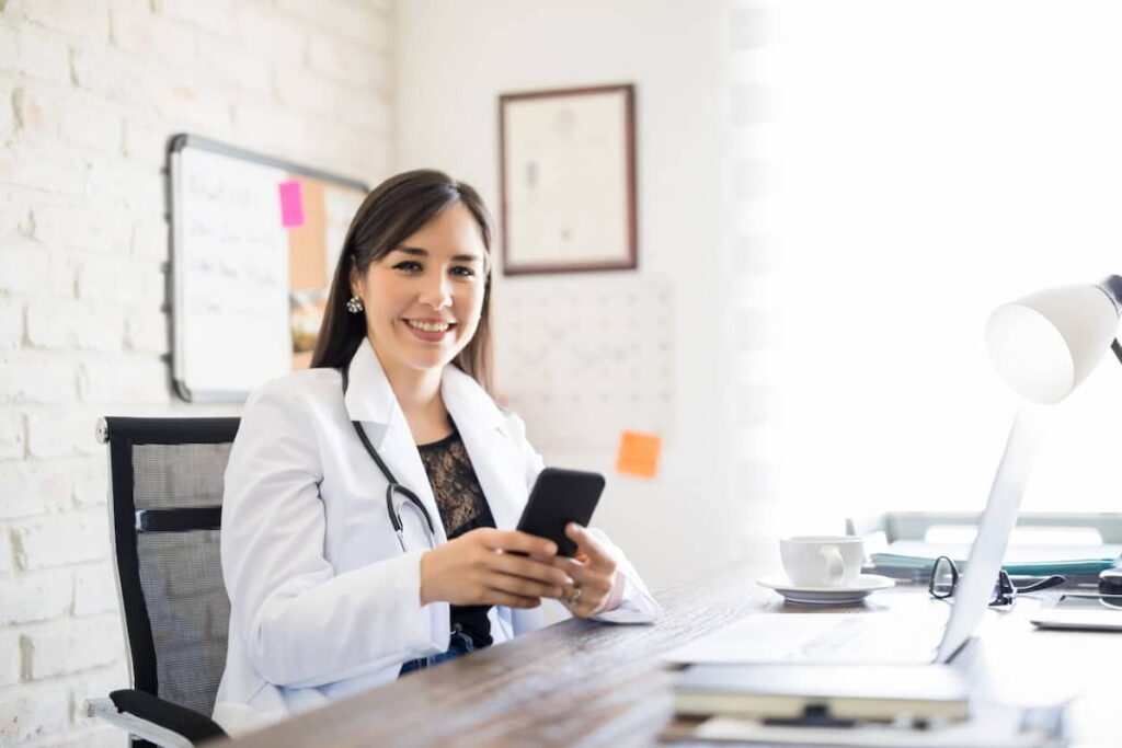 Médica consultando smartphone em escritório, simbolizando redes sociais para médicos.