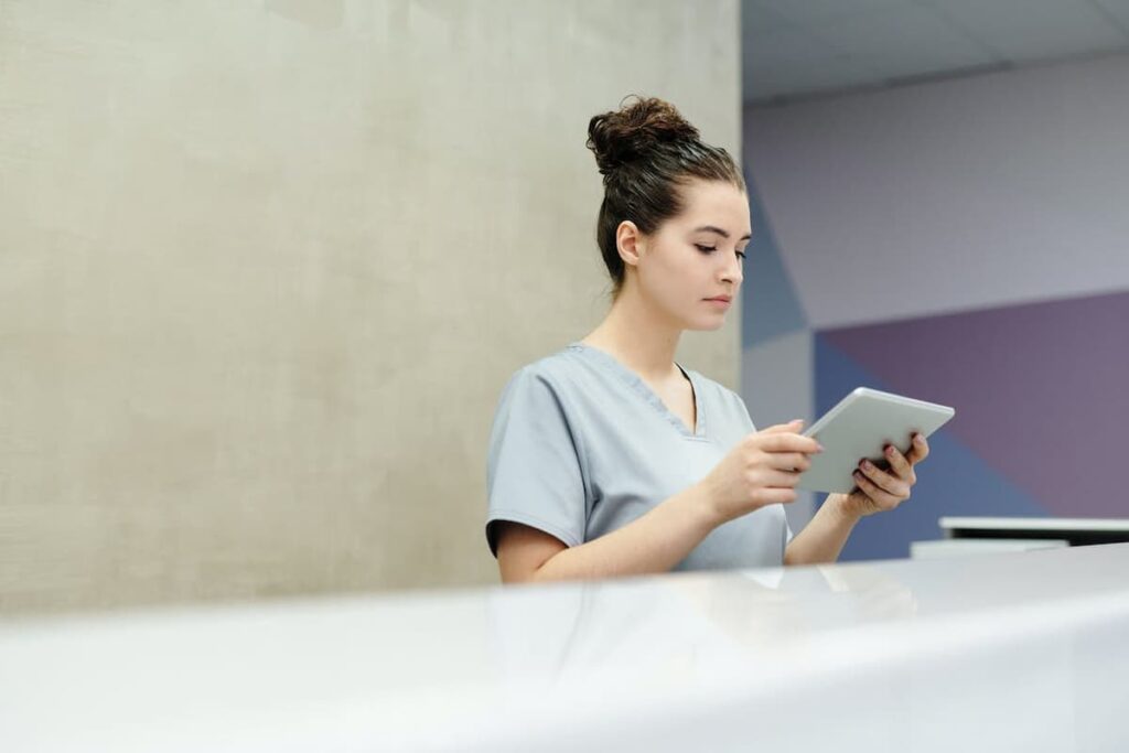 Profissional de saúde consulta sistemas de informação médica em tablet digital.