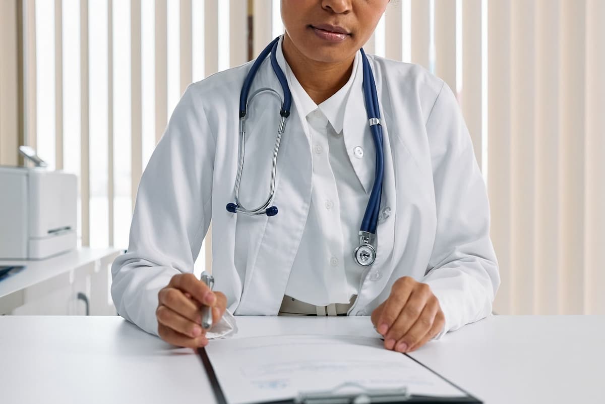 Médico com estetoscópio escrevendo em prontuário, exemplificando gestão de pessoas na clínica médica.