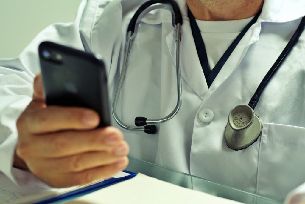 Médico com estetoscópio usando smartphone, representando branding médico e inovação na saúde.