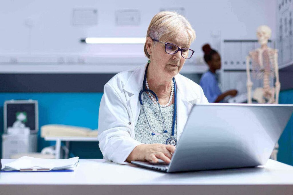 Médico usando laptop para trabalhar em saúde, destacando o papel do IoT na saúde.