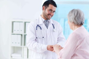 Médico segurando a mão de um paciente idoso, simbolizando cuidado e a jornada do paciente.