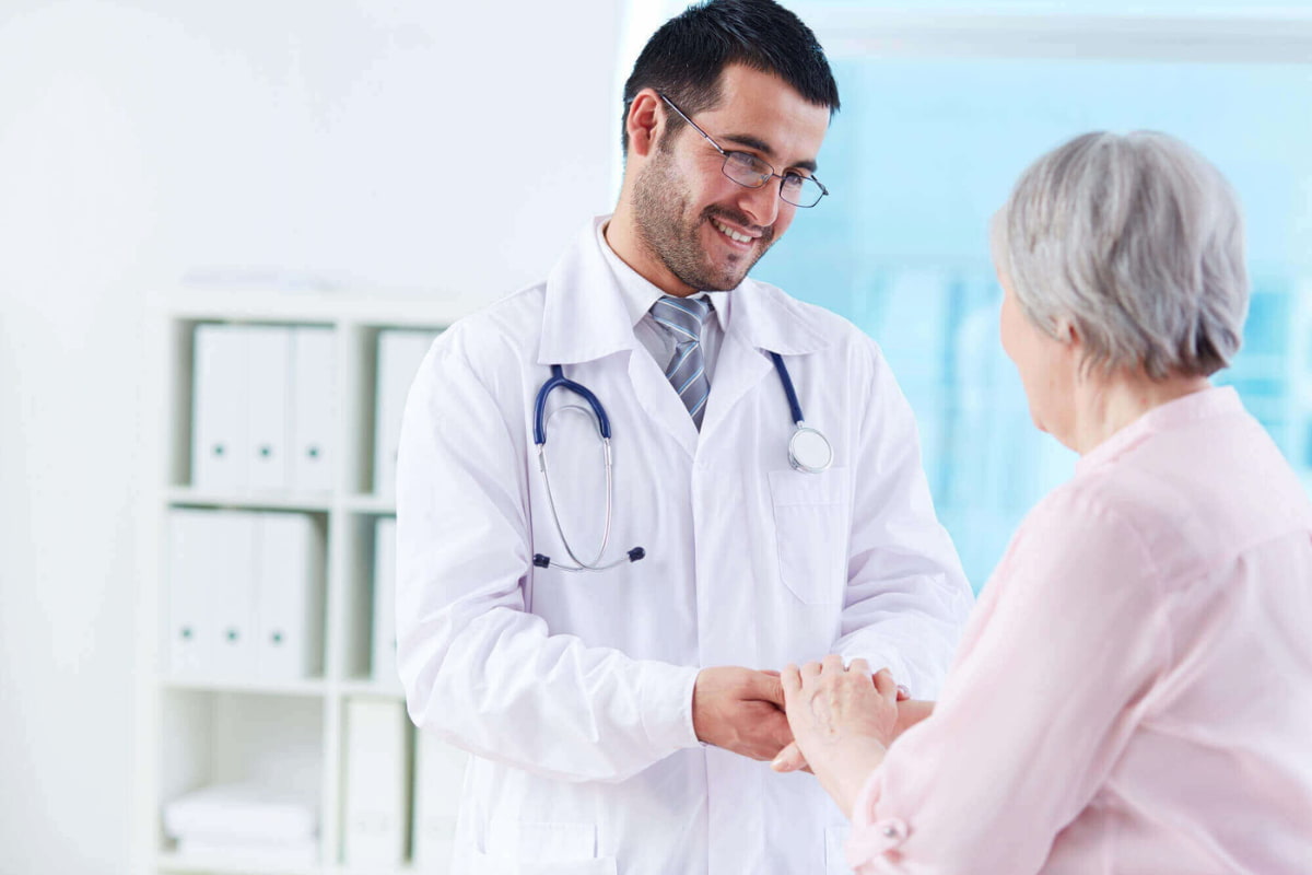 Médico segurando a mão de um paciente idoso, simbolizando cuidado e a jornada do paciente.