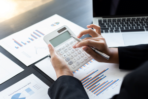 Pessoa com calculadora na mão e documentos ao fundo. Imagem ilustrativa para texto ebitda o que é.