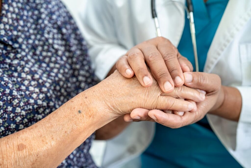 Médico segurando a mão de paciente, simbolizando uma boa relação médico-paciente.