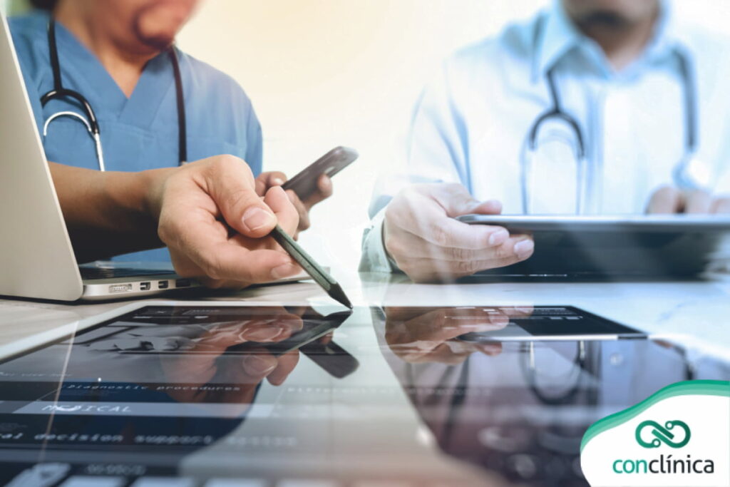 Profissionais de saúde analisando laudo de exame em um tablet digital em ambiente clínico.