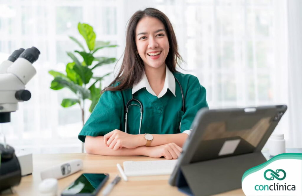 Médica sorrindo em sua mesa de atendimento para telemedicina integrada.