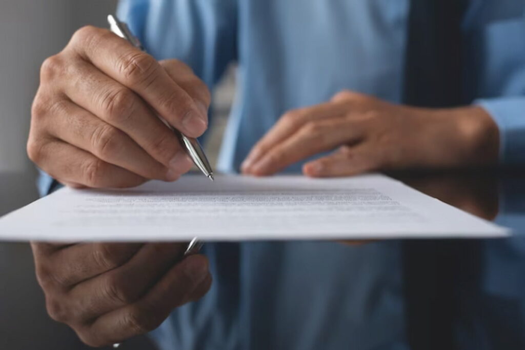 Homem de terno assinando o atestado de comparecimento médico.