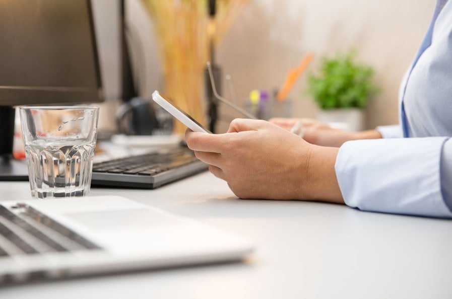 Médico pesquisa em seu celular apoiado na mesa como automatizar agendamento online para atendimento de clínicas