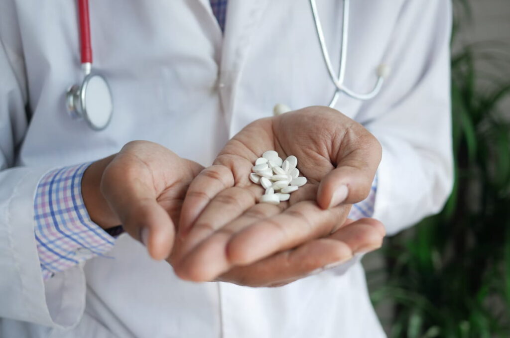 Receita de remédio: médico segurando comprimidos medicamentosos em suas mãos.