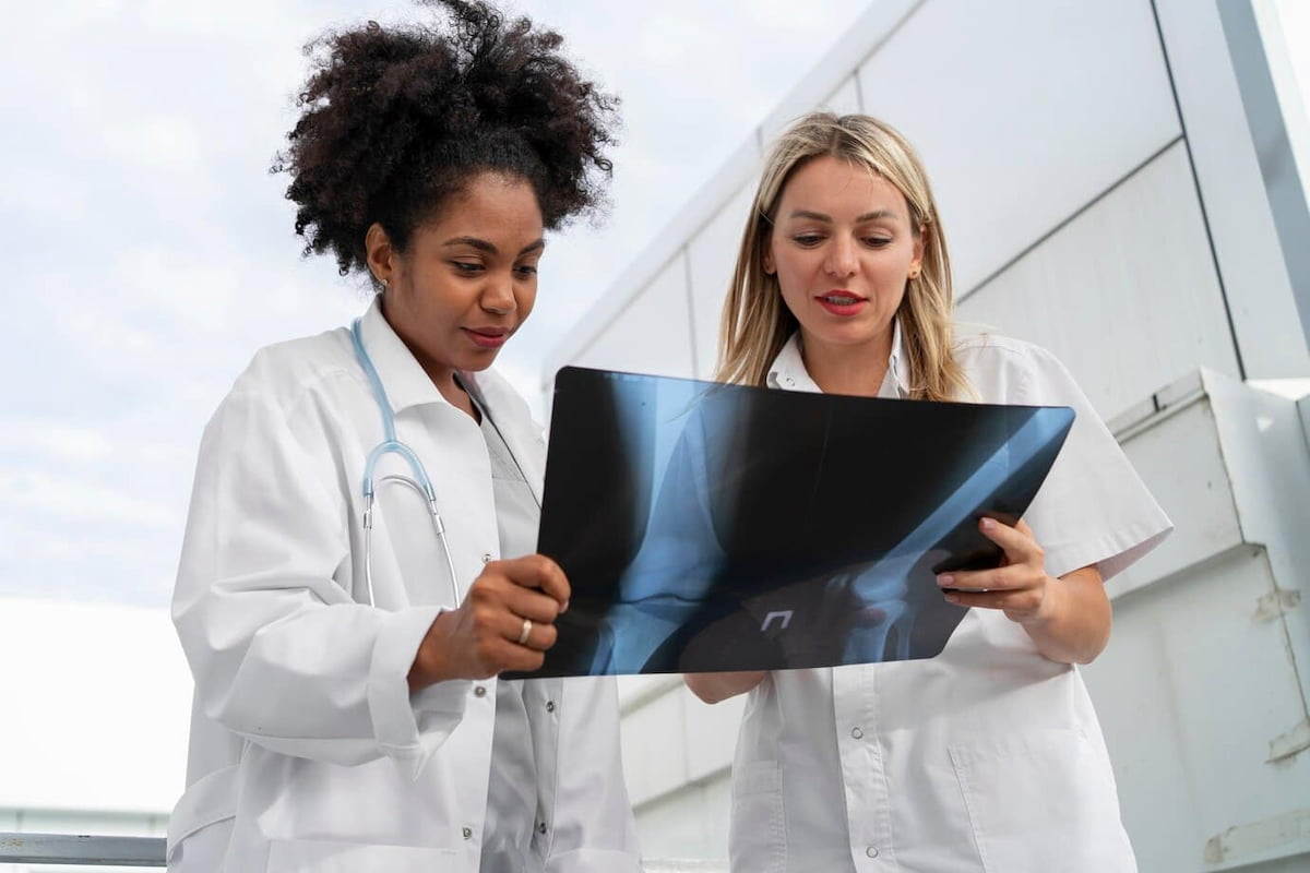 Médicas analisando riscos operacionais na radiologia no exame de radiografia em mãos.