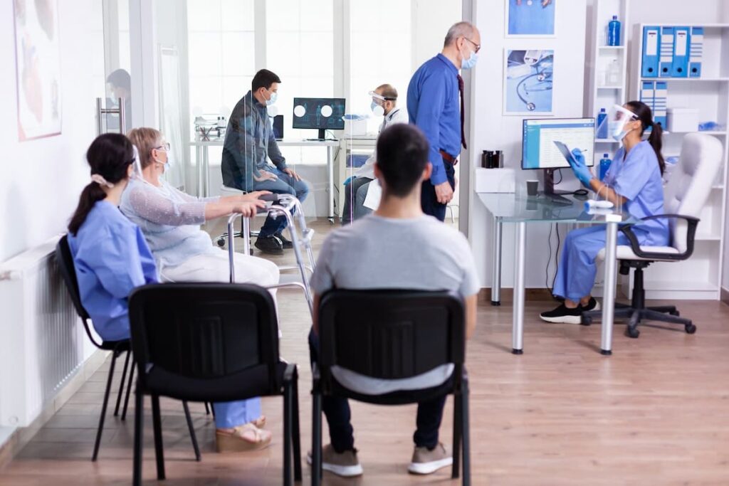 Recepção de clínica organizada com pacientes aguardando e funcionários trabalhando, exemplificando organização eficiente.