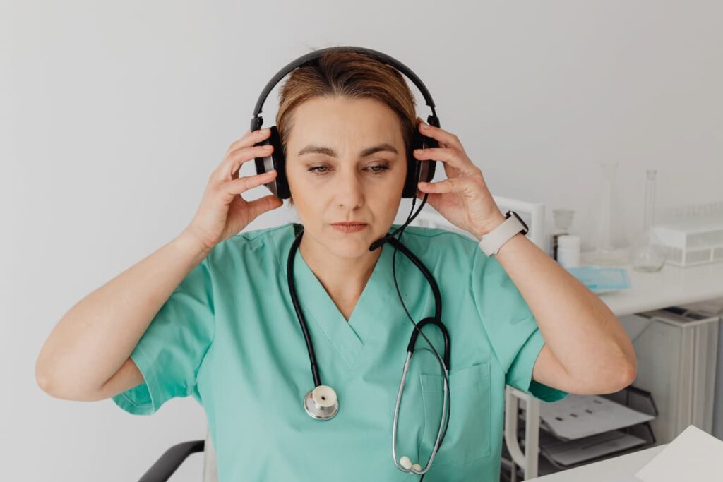 Médica com estetoscópio e fones de ouvido, preparando-se para ouvir um podcast de medicina.