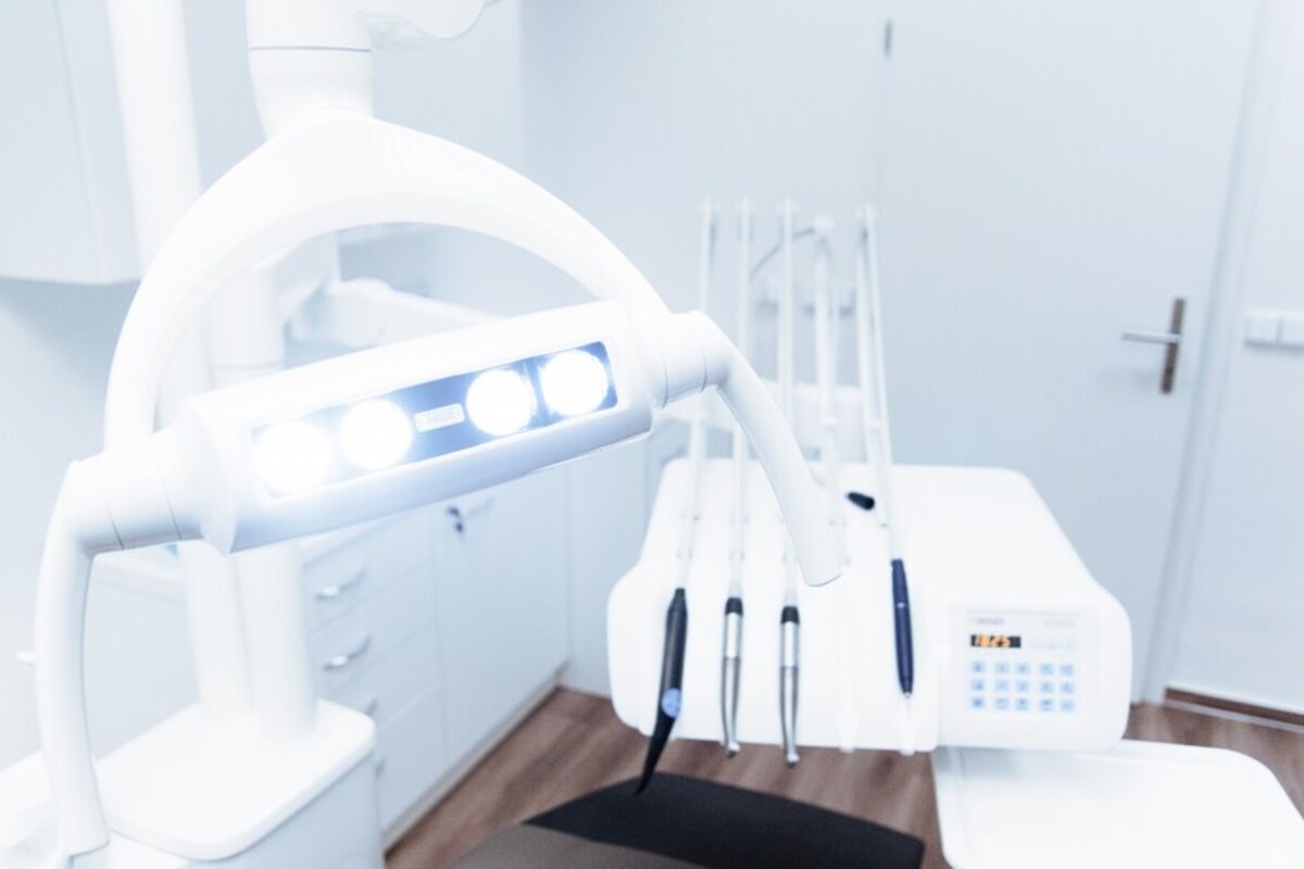 Uma luz de dentista acesa ilumina ao fundo o consultório de quem aprendeu como montar um consultório odontológico