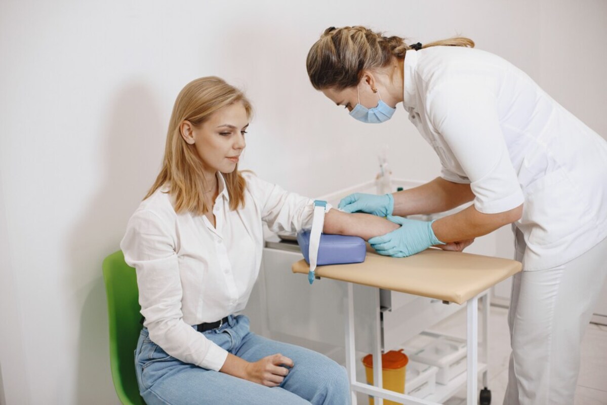 Uma mulher com o braço estendido para uma enfermeira, que conhece os direitos do paciente, fazer o exame de sangue