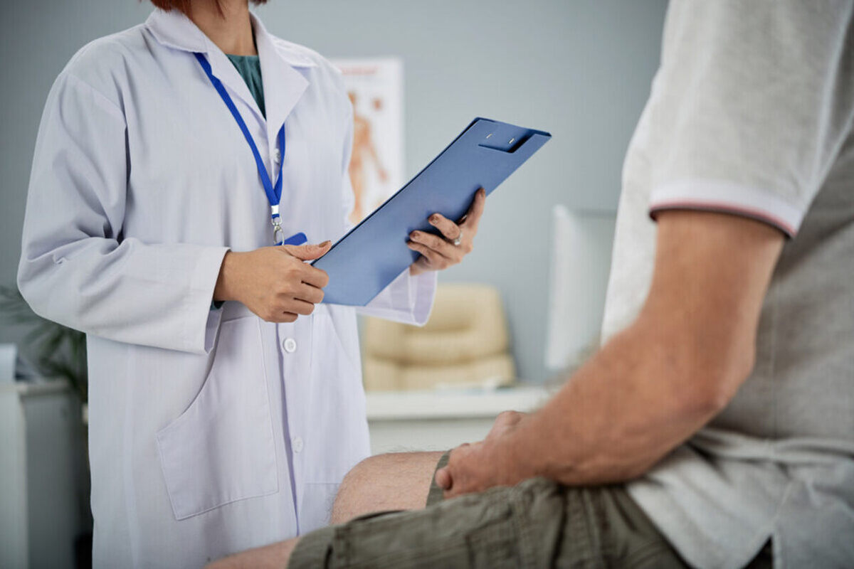 Um médico de jaleco branco faz o diagnóstico médico de um paciente sentado na sua frente
