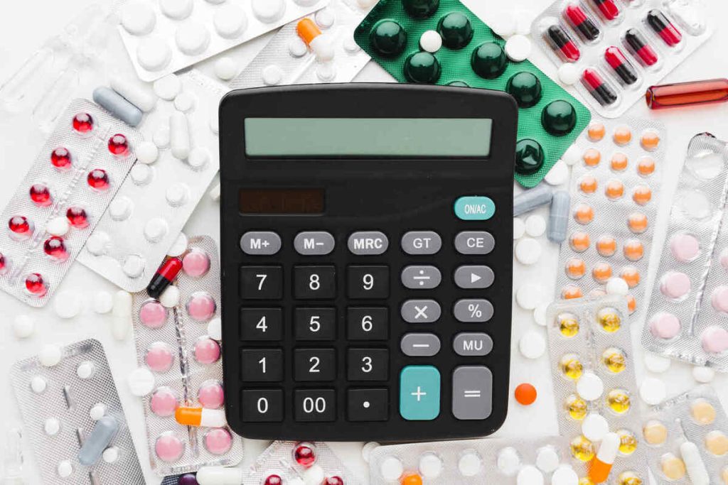 cálculo de medicamentos sendo feito com uma calculadora e remédios ao fundo