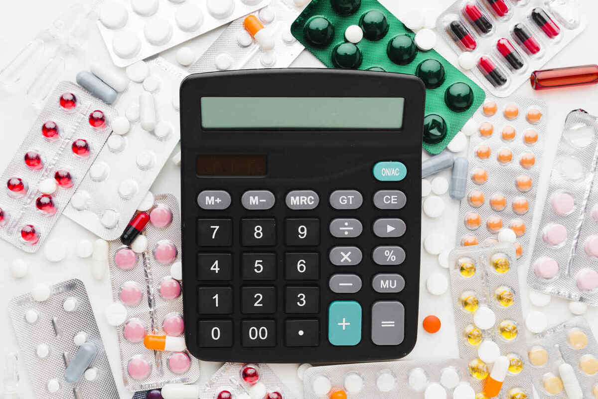 cálculo de medicamentos sendo feito com uma calculadora e remédios ao fundo