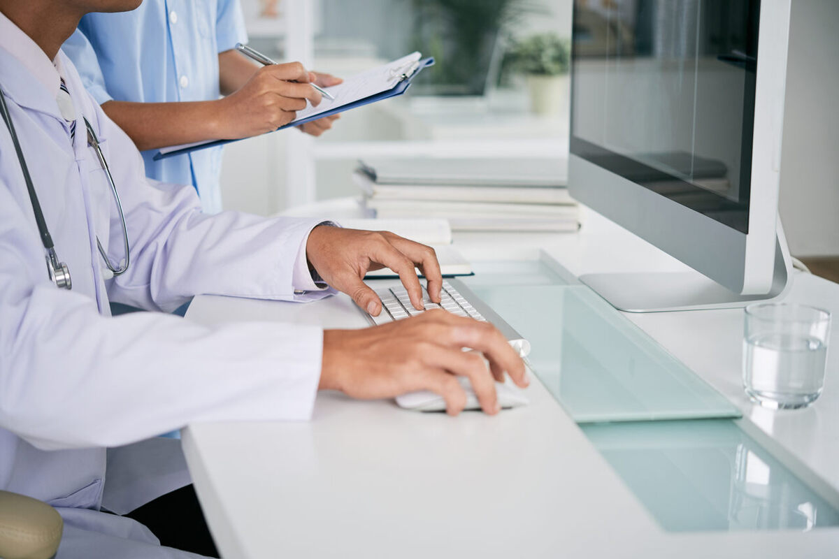Médicos de jaleco branco trabalhando nos computadores da na central de laudos médicos da clínica
