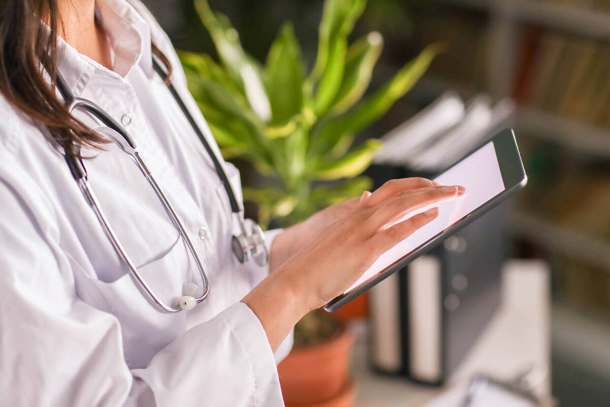 Uma médica de jaleco branco faz a gestao de planos de saúde no tablet da clínica