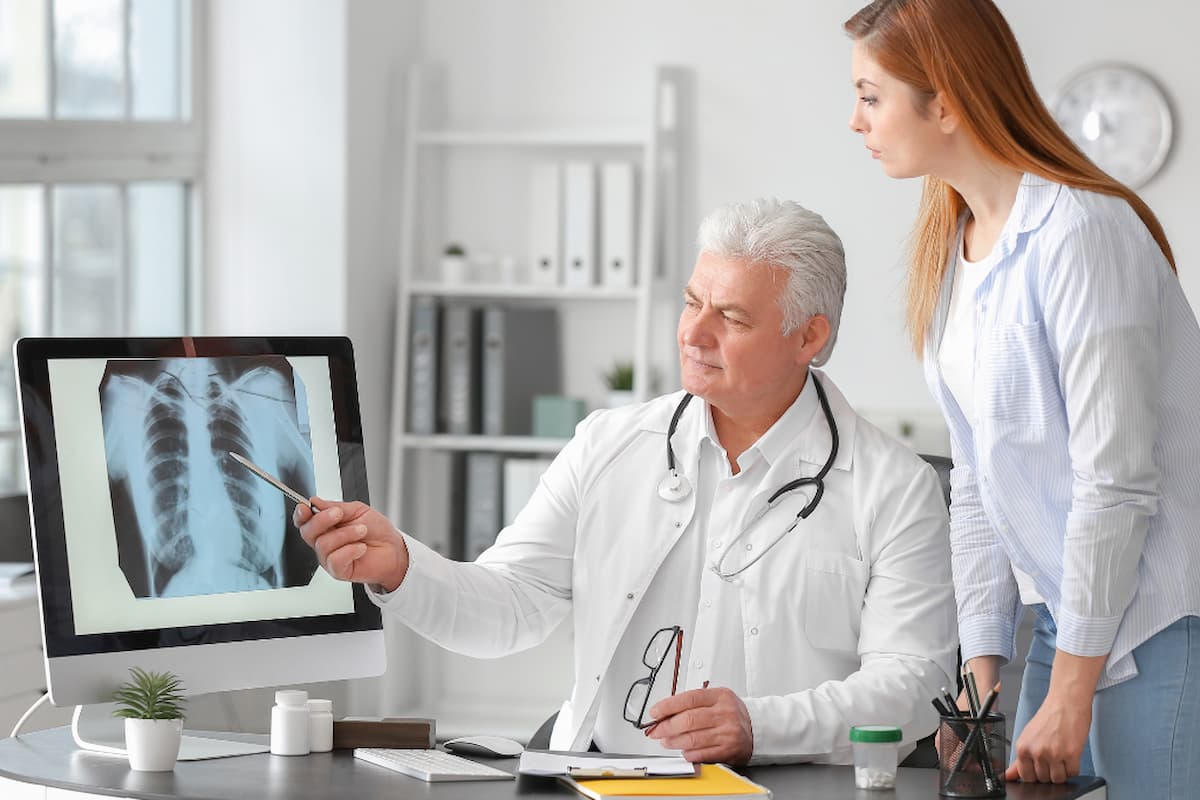 Médico explicando radiografia a paciente em consulta, ilustrando a jornada do paciente no diagnóstico e acompanhamento médico.