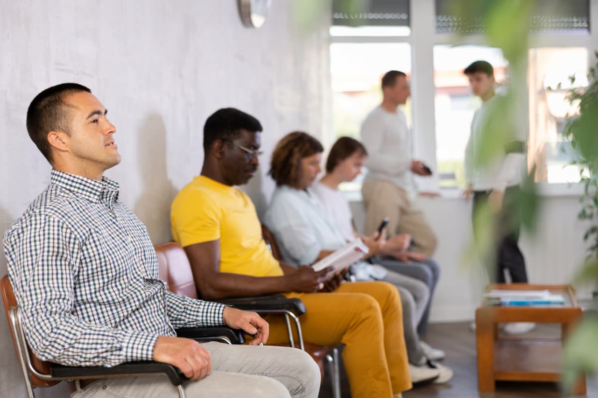 Pessoas aguardando em uma sala de espera de clínica, representando estratégias para reduzir o tempo de espera melhoram o conforto e a satisfação dos pacientes.