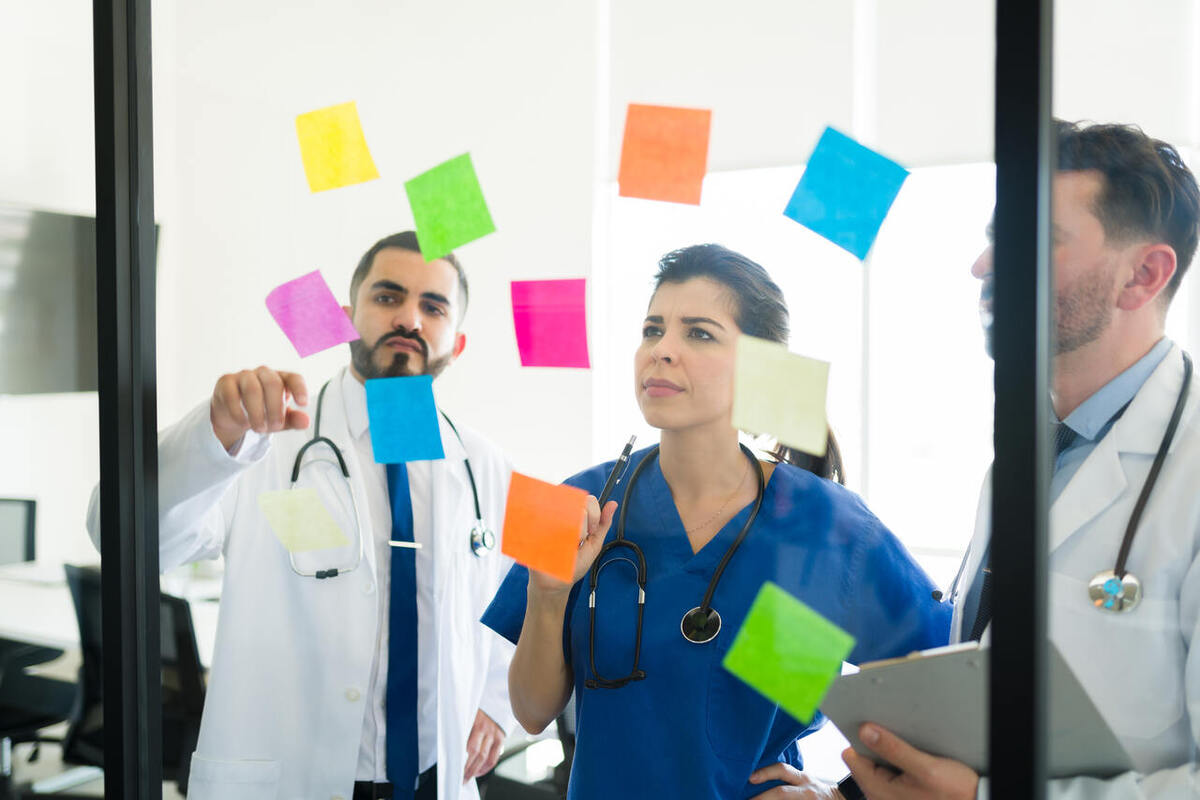 médicos analisando exemplos de empreendedorismo na área da saúde através de post its colados no vidro