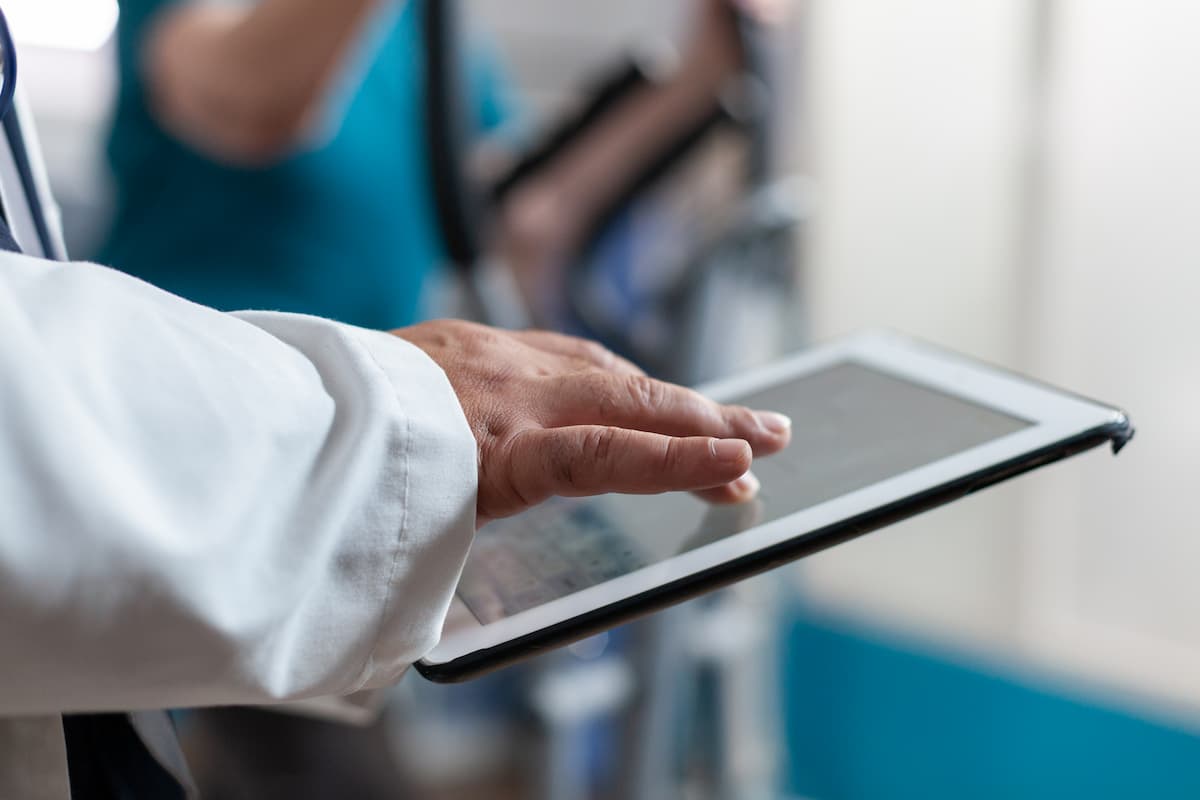 Médico usando um tablet para gestão financeira com software para fluxo de caixa de clínicas, otimizando processos administrativos.