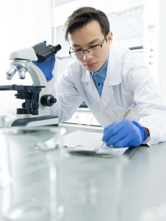 Profissional médico anotando observações durante estudos com microscópio, em prol dos avanços tecnológicos na saúde