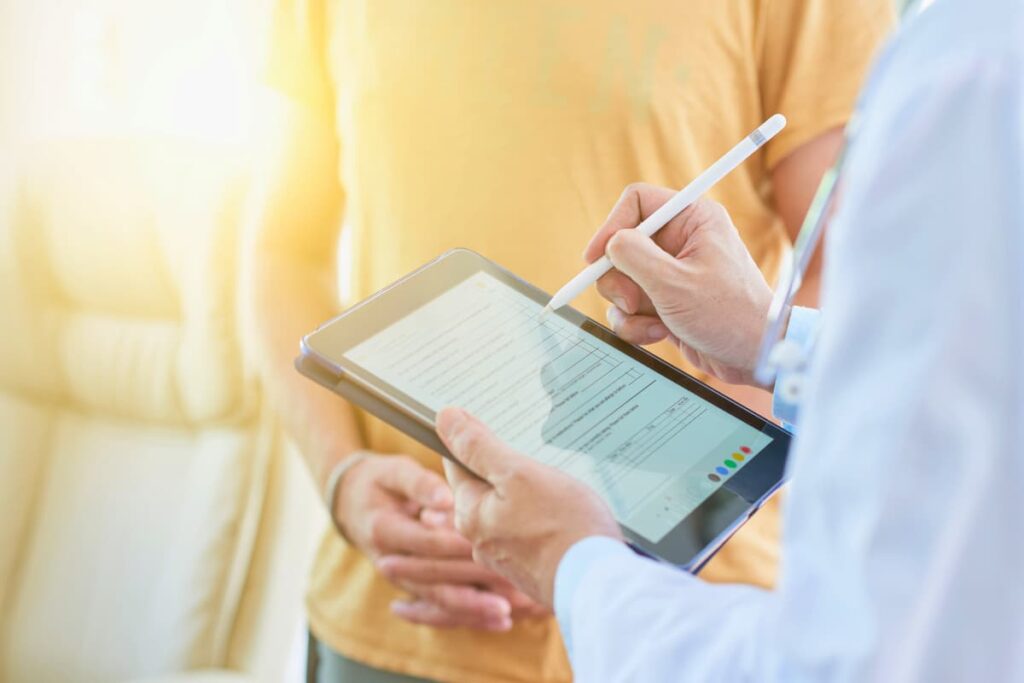 Médico preenche prontuário eletrônico do paciente em um tablet, representando as vantagens e desvantagens dessa tecnologia.