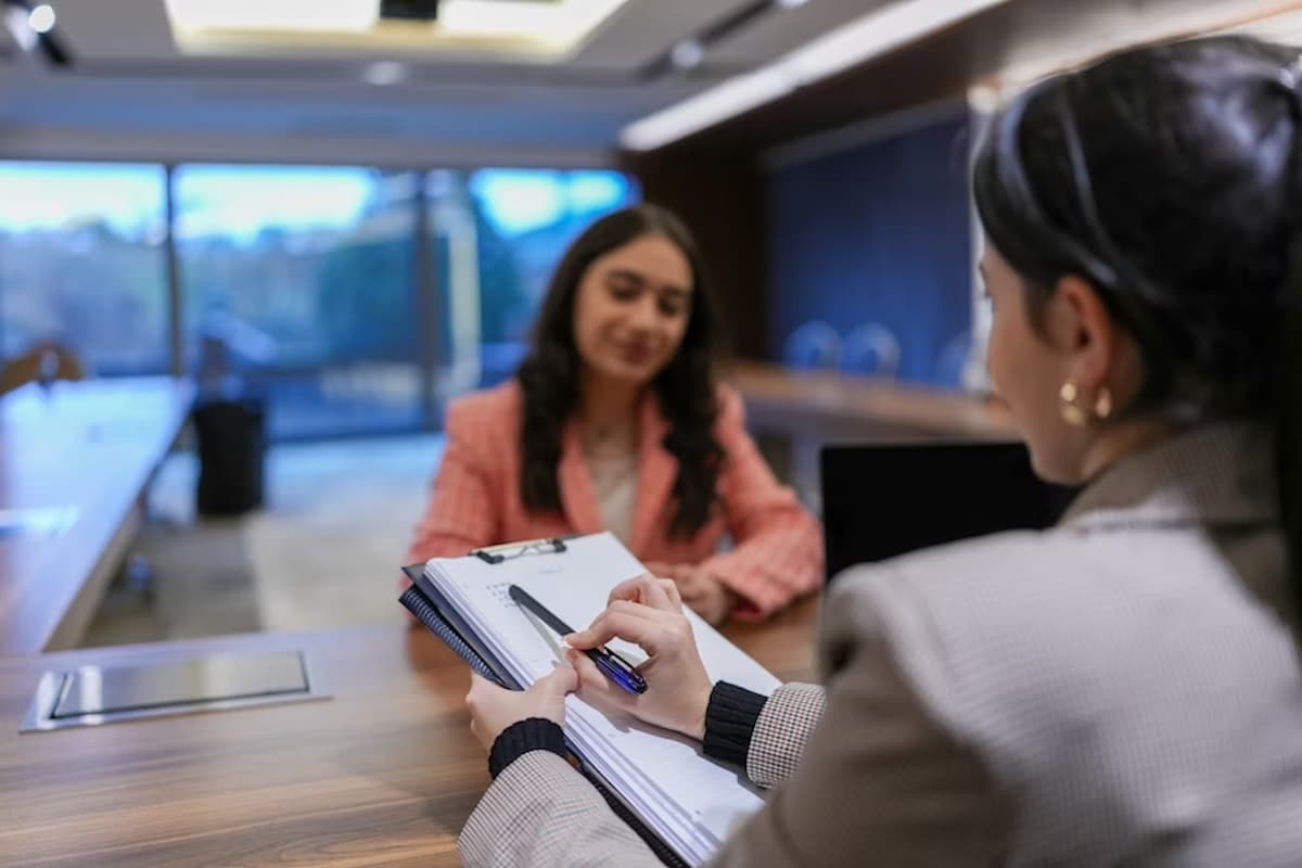 Na imagem, vemos uma cena que pode representar um atendimento em uma clínica médica ou psicológica, embora o ambiente também tenha características corporativas. A atmosfera é profissional e organizada, sugerindo um momento de entrevista, consulta ou triagem.