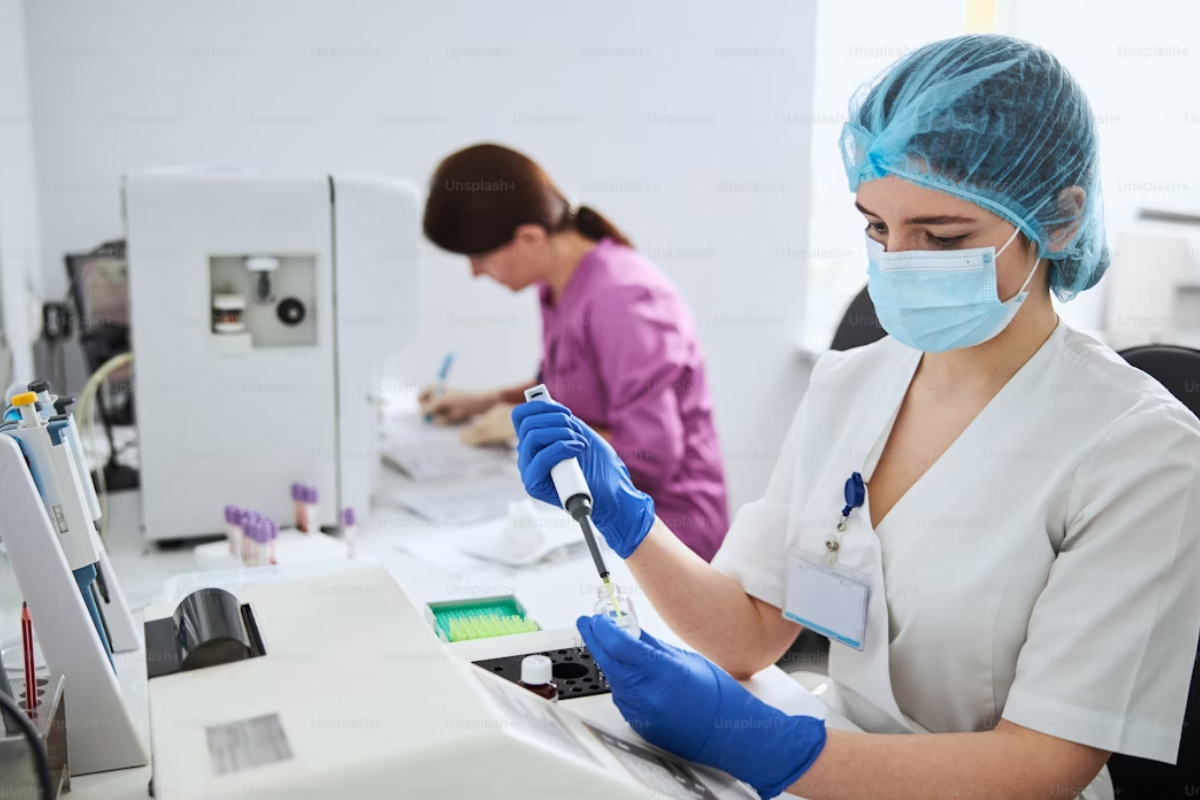 A imagem retrata duas pessoas em um ambiente que parece ser um laboratório de análises clínicas ou de pesquisa.
