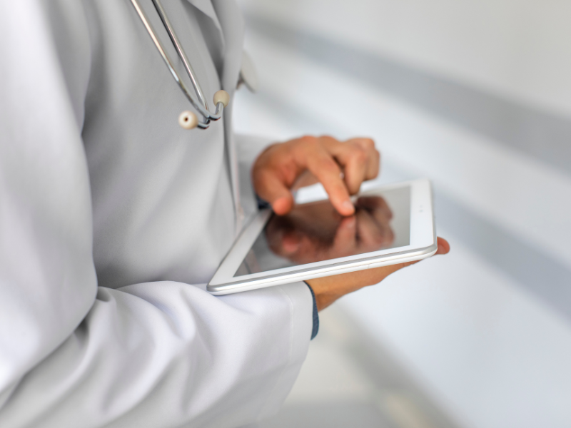 O arquivo de imagem enviado é um close-up que foca na interação de um profissional de saúde com um tablet.