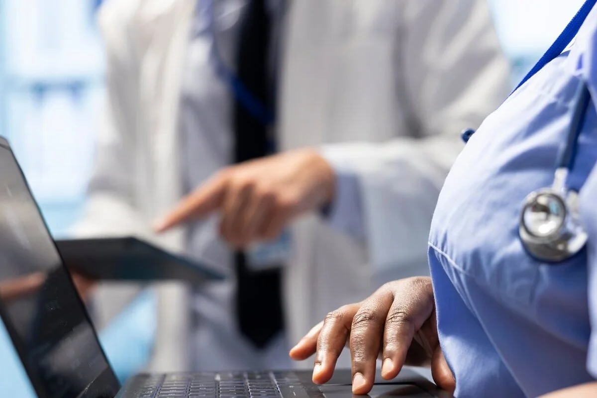 m&eacute;dico e enfermeira avaliando um prontu&aacute;rio eletr&ocirc;nico interoper&aacute;vel pelo notebook