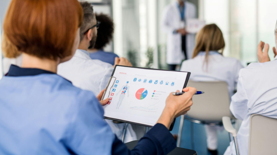 Esta imagem retrata uma conferência ou treinamento na área da saúde, focada no compartilhamento de dados e análises médicas.