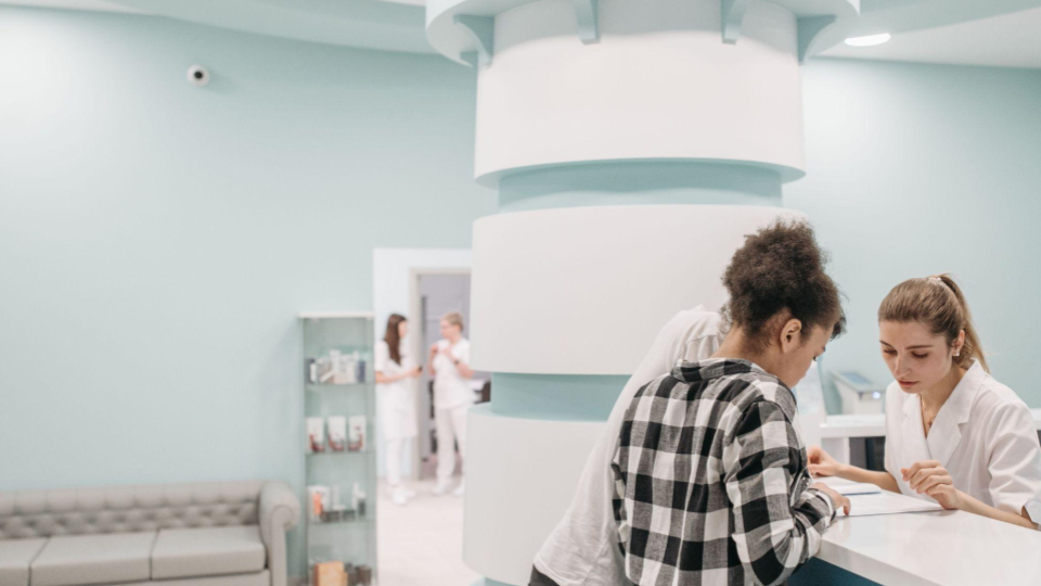 A imagem mostra o ambiente de recepção e atendimento de uma clínica médica, hospital ou centro de estética moderno e bem estruturado.