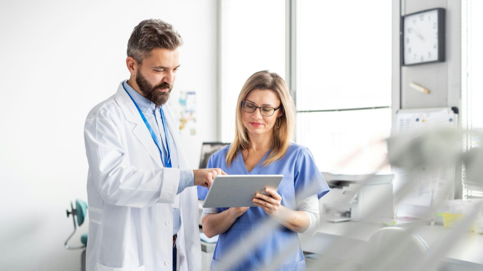 Médicos utilizando um tablet para analisar informações da clínica, representando o uso de tecnologia e indicadores para apoiar decisões estratégicas e a expansão de clínicas com mais segurança.