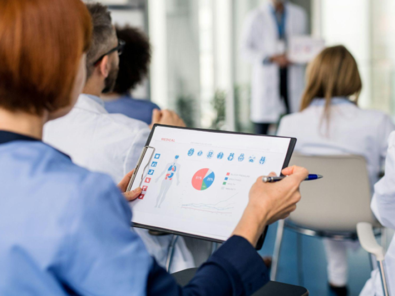 Esta imagem retrata uma conferência ou treinamento na área da saúde, focada no compartilhamento de dados e análises médicas.