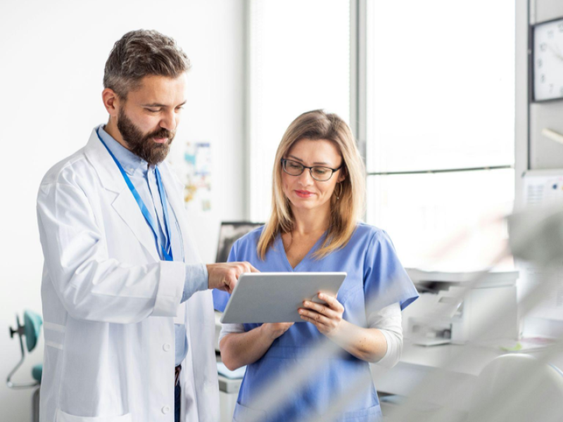 Médicos utilizando um tablet para analisar informações da clínica, representando o uso de tecnologia e indicadores para apoiar decisões estratégicas e a expansão de clínicas com mais segurança.